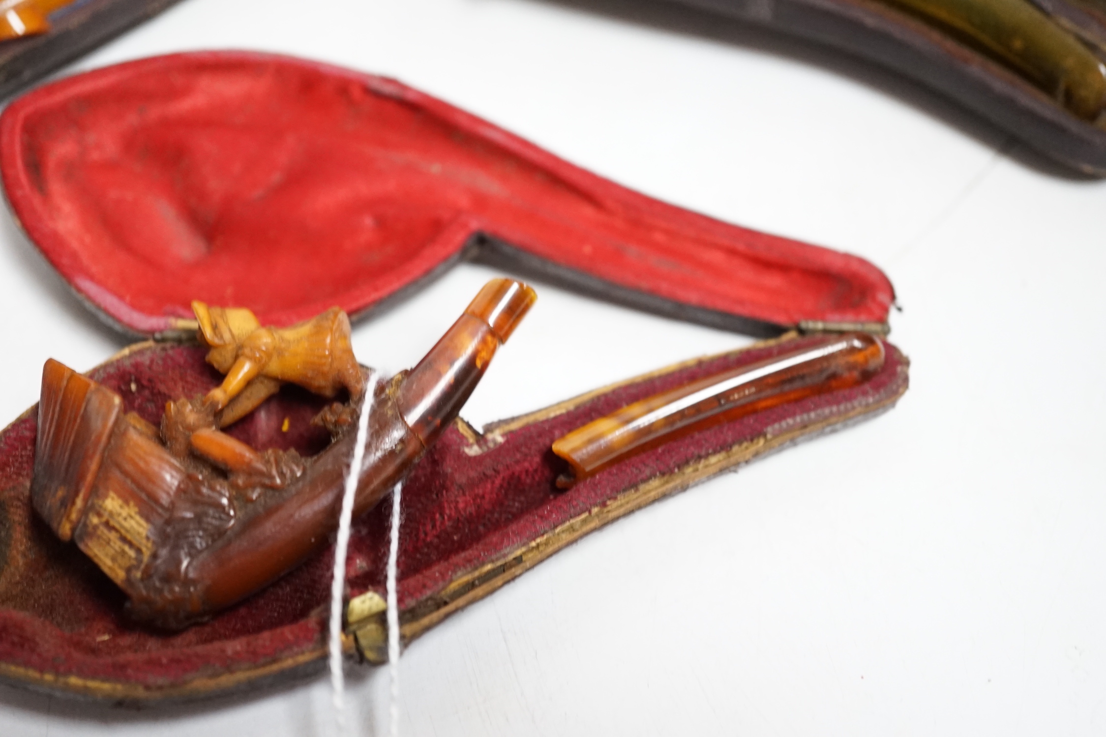 Three cased pipes, one with carved amber novelty bowl, the other two with amber pipe ends, metal mounted, together with a tortoiseshell and mother of pearl card case, Card case 10.5cm high x 8cm wide